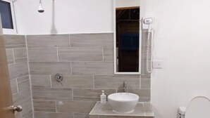 A bathroom with a shower, a toilet, a sink, and a telephone.