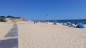 Une plage avec une promenade en bois, des parasols et des gens qui se détendent.