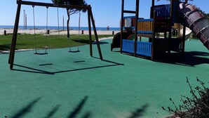 A playground with swings and a play structure near a beach. - T1 SOL 200m Praia Vista MAR Wi-fi (Loulé)