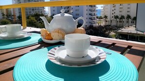 A balcony with a table set for tea, including a teapot, cups, and biscuits. - T1 SOL 200m Praia Vista MAR Wi-fi (Loulé)
