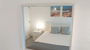 A bedroom with a bed, a nightstand, a lamp, and two framed pictures on the wall.