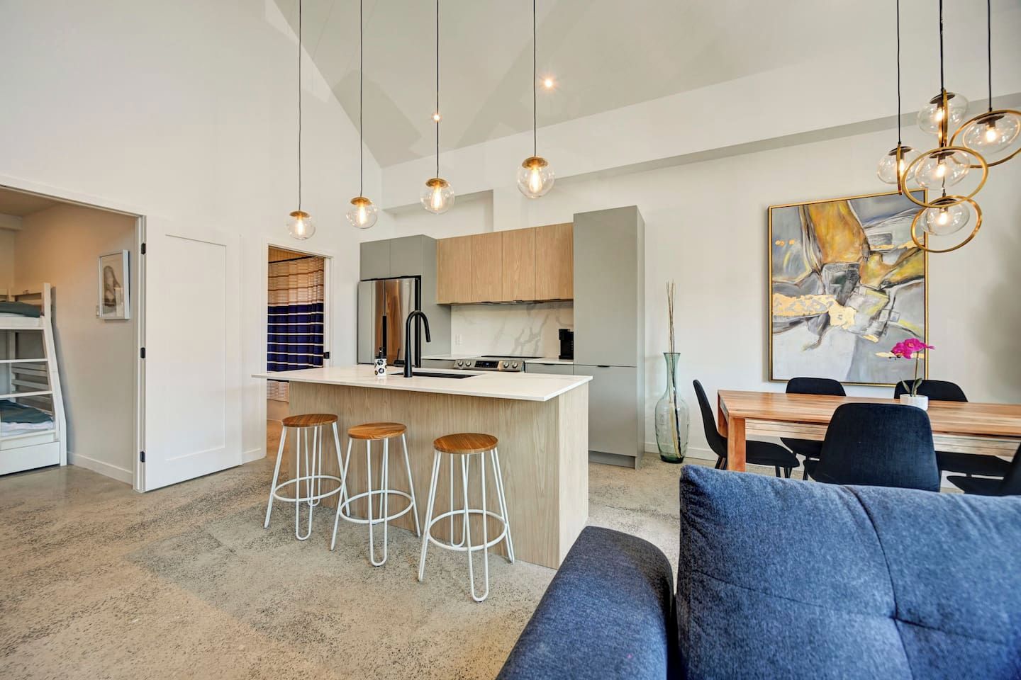 A modern kitchen with a central island, bar stools, and pendant lighting.