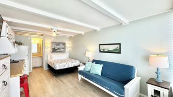 Ein kleiner Raum mit einem Bett, einer Schlafcouch, einem kleinen Tisch und einer Küchenzeile.