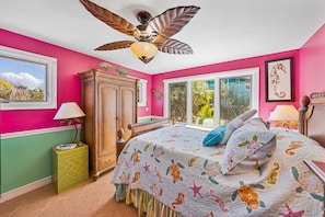 A bedroom with a bed, a ceiling fan, a window, and a view of the outside.