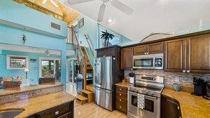 A modern kitchen with stainless steel appliances, wooden cabinets, and a granite countertop. - The Salty Conch - Luxury Just Steps To The Beach with Private Pool;2 Golf Carts (Captiva)