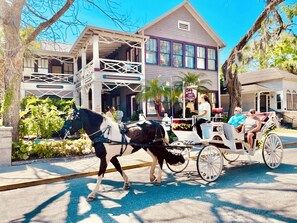 A horse-drawn carriage on a street with a building in the background.