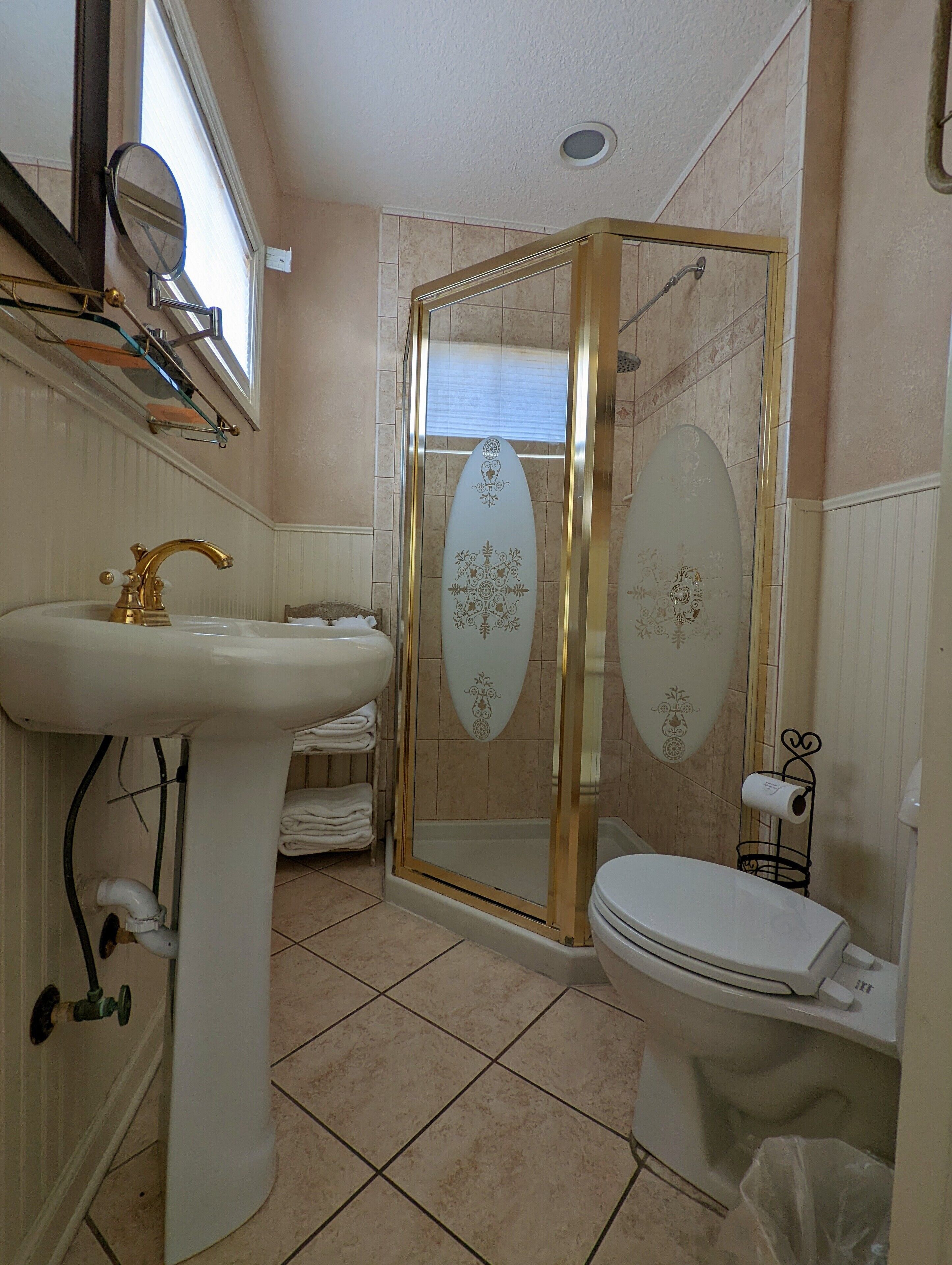 A bathroom with a pedestal sink, toilet, and a shower enclosure with frosted glass doors.