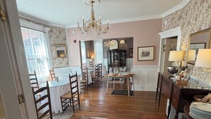 A dining area with a chandelier, wooden chairs, a table set for four, and a patterned rug. - Old Powder House Inn (St. Augustine)