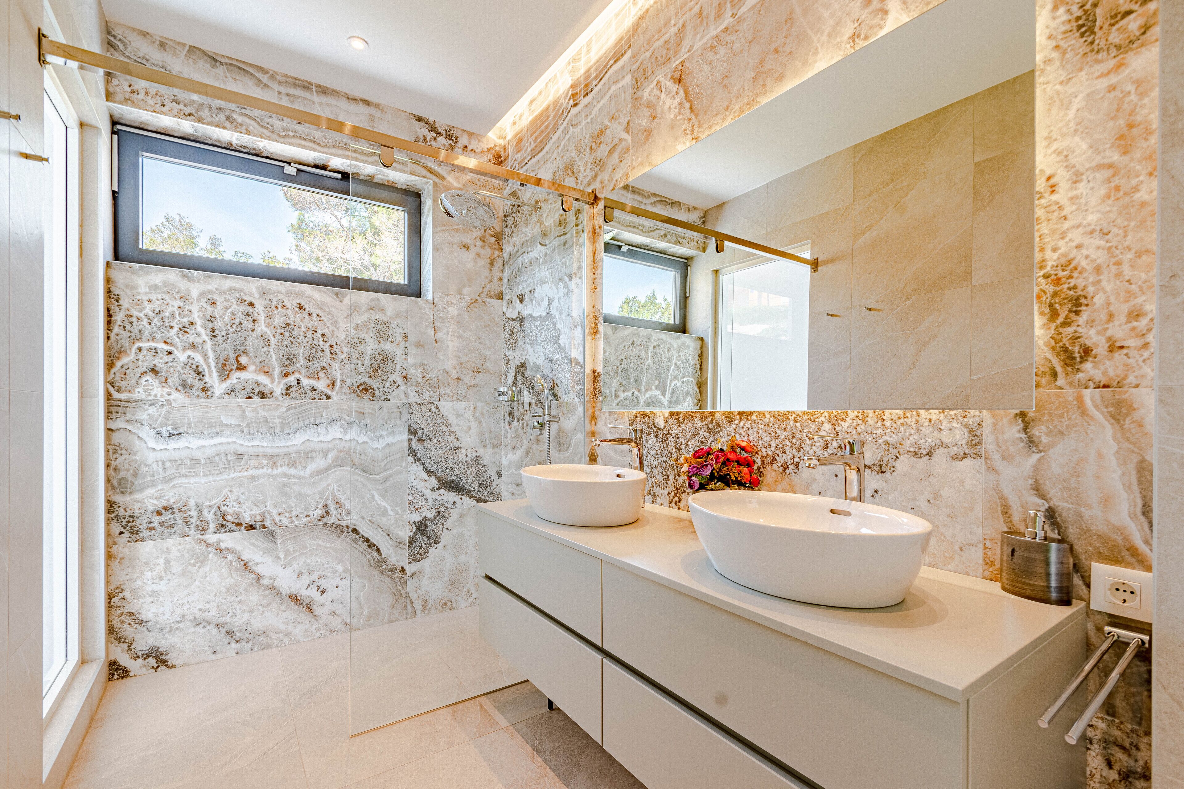 A modern bathroom with two large white sinks, a large mirror, and a window.
