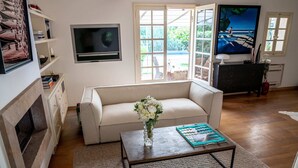 A living room with a fireplace, a sofa, a coffee table, and a TV. - Villa Les Muscadines Saint Tropez, Tahiti Pampelonne beach, heated pool. (Saint-Tropez)