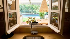A kitchen with an open window, a sink, and a hanging light fixture. - Villa Les Muscadines Saint Tropez, Tahiti Pampelonne beach, heated pool. (Saint-Tropez)