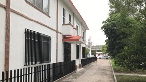 Ein Gebäude mit weißer Fassade, schwarzen Metallgeländern und einem roten Markisenaufbau.