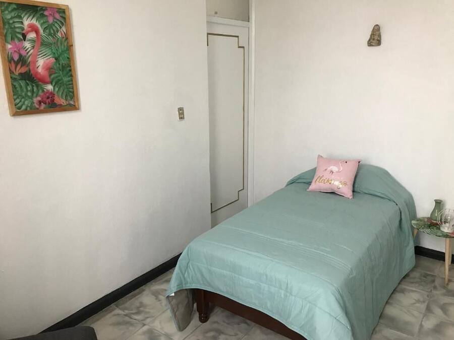 Un dormitorio con una cama, una puerta y un cuadro colgado en la pared.