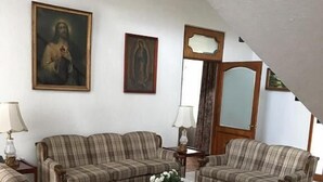 Ein Wohnzimmer mit zwei Sofas, einem Couchtisch und zwei Lampen. An der Wand hängen zwei gerahmte Bilder.