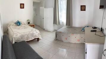 A small, clean room with a bed, a sofa, a desk, and a chair.