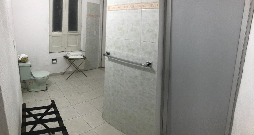 A bathroom with a toilet, a window, and a towel rack.