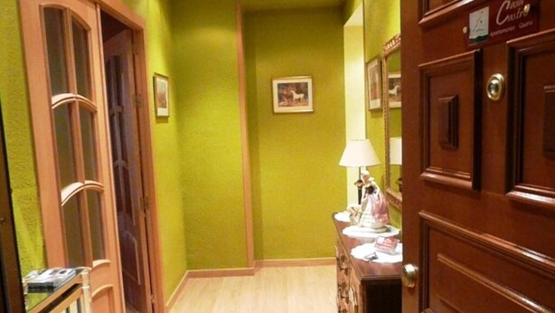 A hallway with wooden doors, a wooden dresser, and a lamp. - GUARA CASA CASTRO TOURIST APARTMENT, IN THE HEART OF SOMONTANO. (Barbastro)
