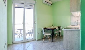 Uma cozinha compacta com área de refeições, pia e janela com vista para uma varanda.