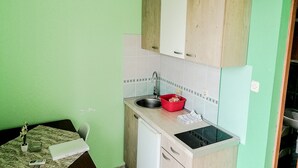 Une cuisine compacte avec un évier, un égouttoir à vaisselle rouge et un petit plan de travail.