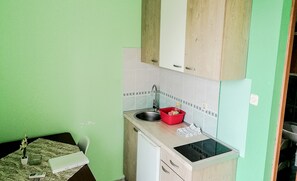 Uma cozinha compacta com pia, escorredor de louça vermelho e bancada pequena.