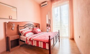 Un dormitorio con una cama de madera, una mesita de noche, un espejo y una ventana con cortinas.