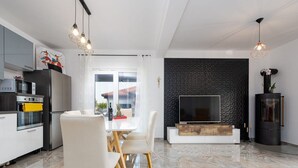 A modern kitchen with a dining area, a large TV, and a black textured wall.