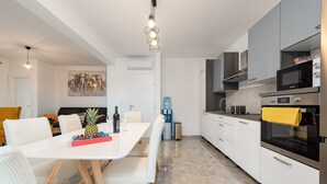 A modern kitchen with white cabinets, a large island with seating, and stainless steel appliances.