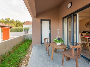 Enjoy a tranquil outdoor space with a round table and four chairs, surrounded by lush greenery and a grassy area.