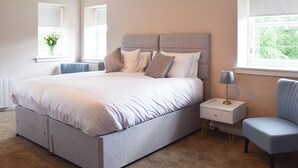 A modern bedroom with a large bed, bedside tables, a chair, and a window with a view. - 1 bedroom accommodation in Aberfoyle (Aberfoyle)