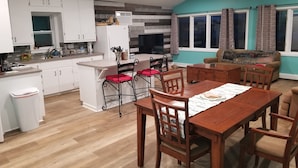 A modern kitchen with white cabinets, a wooden dining table, and a built-in island with red cushioned chairs. - 4 Season newly remodeled all sport lake cottage w/ nearby golfing & snowmobiling (Alto)