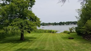 A grassy lawn with a tree and a view of a lake with boats. - 4 Season newly remodeled all sport lake cottage w/ nearby golfing & snowmobiling (Alto)