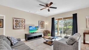 Ein Wohnzimmer mit Sofa, Couchtisch, Fernseher und Deckenventilator.