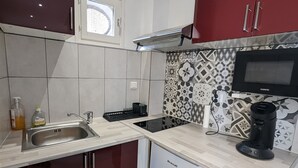 A compact kitchen with a built-in microwave, a coffee maker, and a dishwasher. - Atypical apartment house (Annonay)