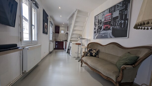 A hallway with a sofa, a washing machine, and a radiator. - Atypical apartment house (Annonay)
