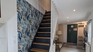 A staircase with a patterned wall, a washing machine, and a door leading to another room. - Atypical apartment house (Annonay)