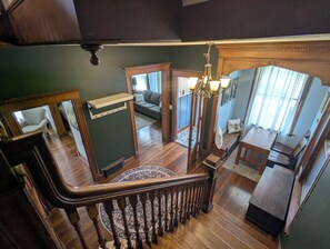 Uma escadaria com corrimão de madeira, um lustre e um espaço de jantar com mesa e cadeiras.