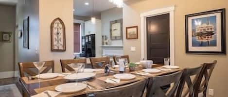 A dining area with a wooden table set for six, surrounded by chairs.