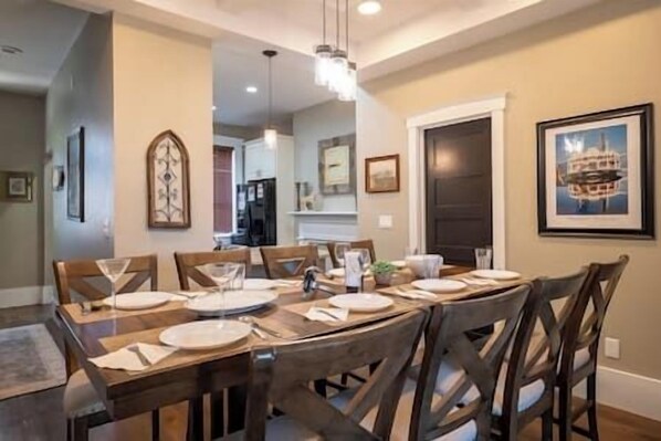 A dining area with a wooden table set for six, surrounded by chairs.