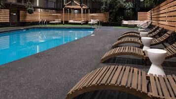 Uma área de piscina com espreguiçadeiras de madeira e um deck de madeira.