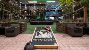 A spacious indoor area with multiple levels, featuring a central courtyard with a cactus-themed design, surrounded by seating areas and a pool. - The Cactus Cove Inn and Suites (Amarillo)