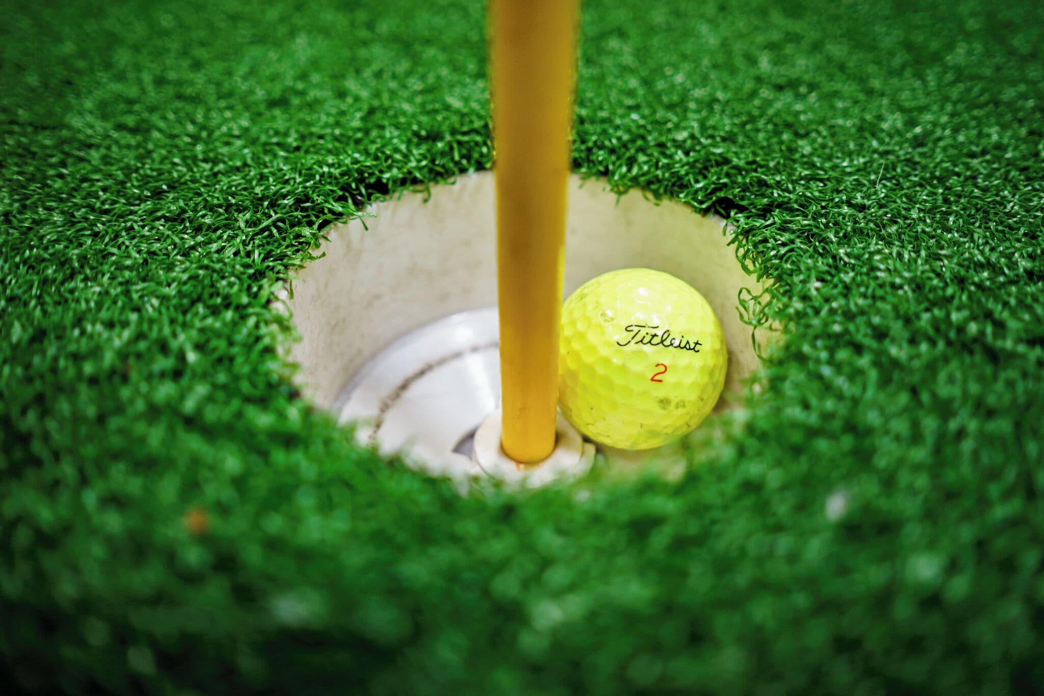 A golf ball labeled 'Titleist' in a hole on a green surface.