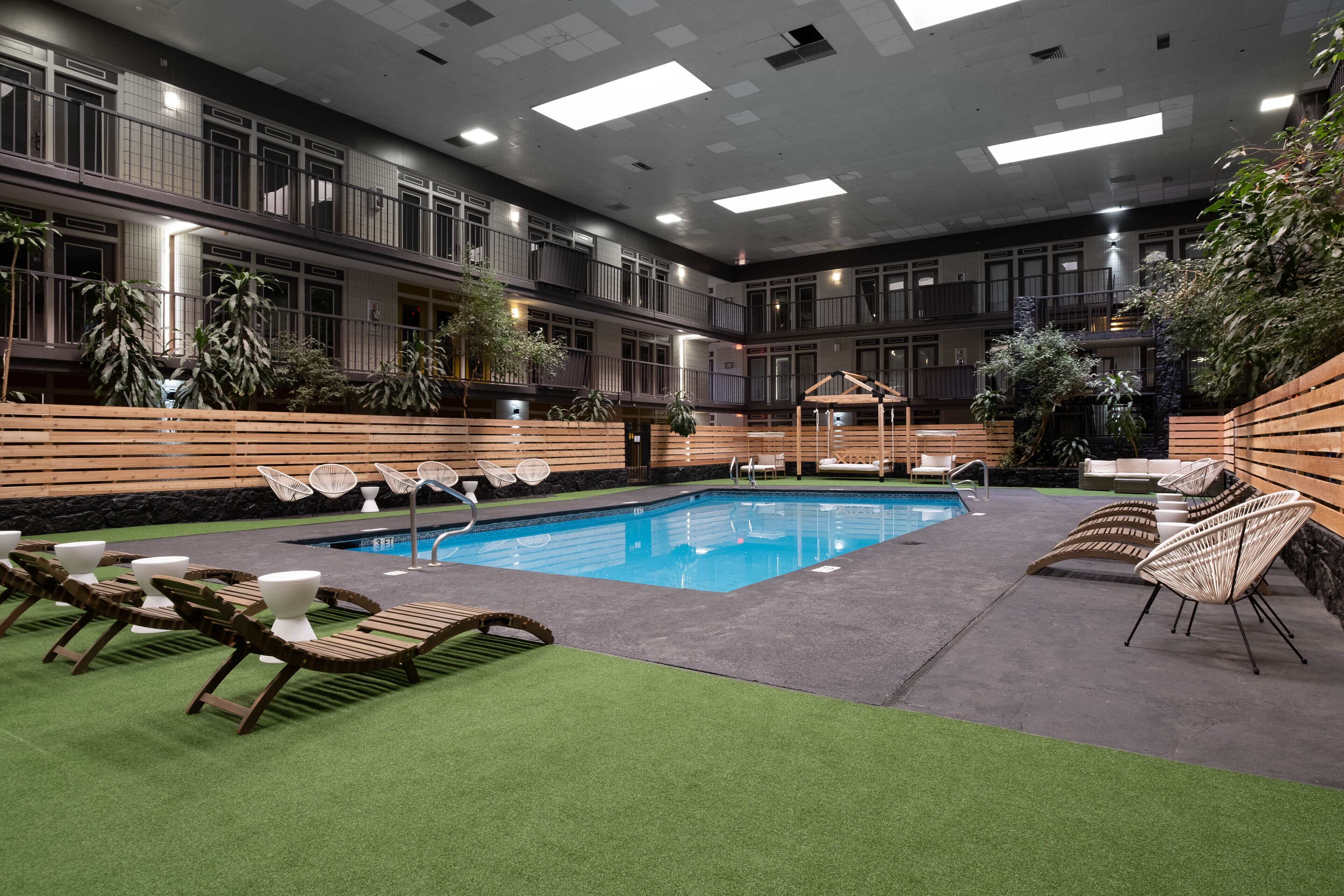 A modern indoor pool area with multiple lounge chairs and a small pool.