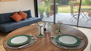 A dining table set with green plates, silverware, and a green wine glass, surrounded by a blue sofa with orange cushions. - Self-contained annex close to town centre (Eastbourne)
