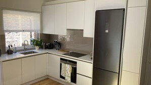 A modern kitchen with white cabinets, a stainless steel refrigerator, a sink, and a window with a view of a brick building. - Self-contained annex close to town centre (Eastbourne)
