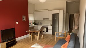 A modern living room with a TV, sofa, and dining area. - Self-contained annex close to town centre (Eastbourne)