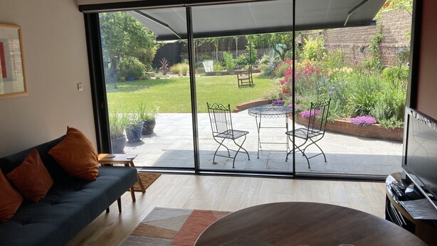 A modern living room with a large sliding glass door leading to an outdoor patio area. - Self-contained annex close to town centre (Eastbourne)