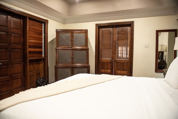 A bedroom with a large bed, wooden wardrobes, and a mirror on the wall.