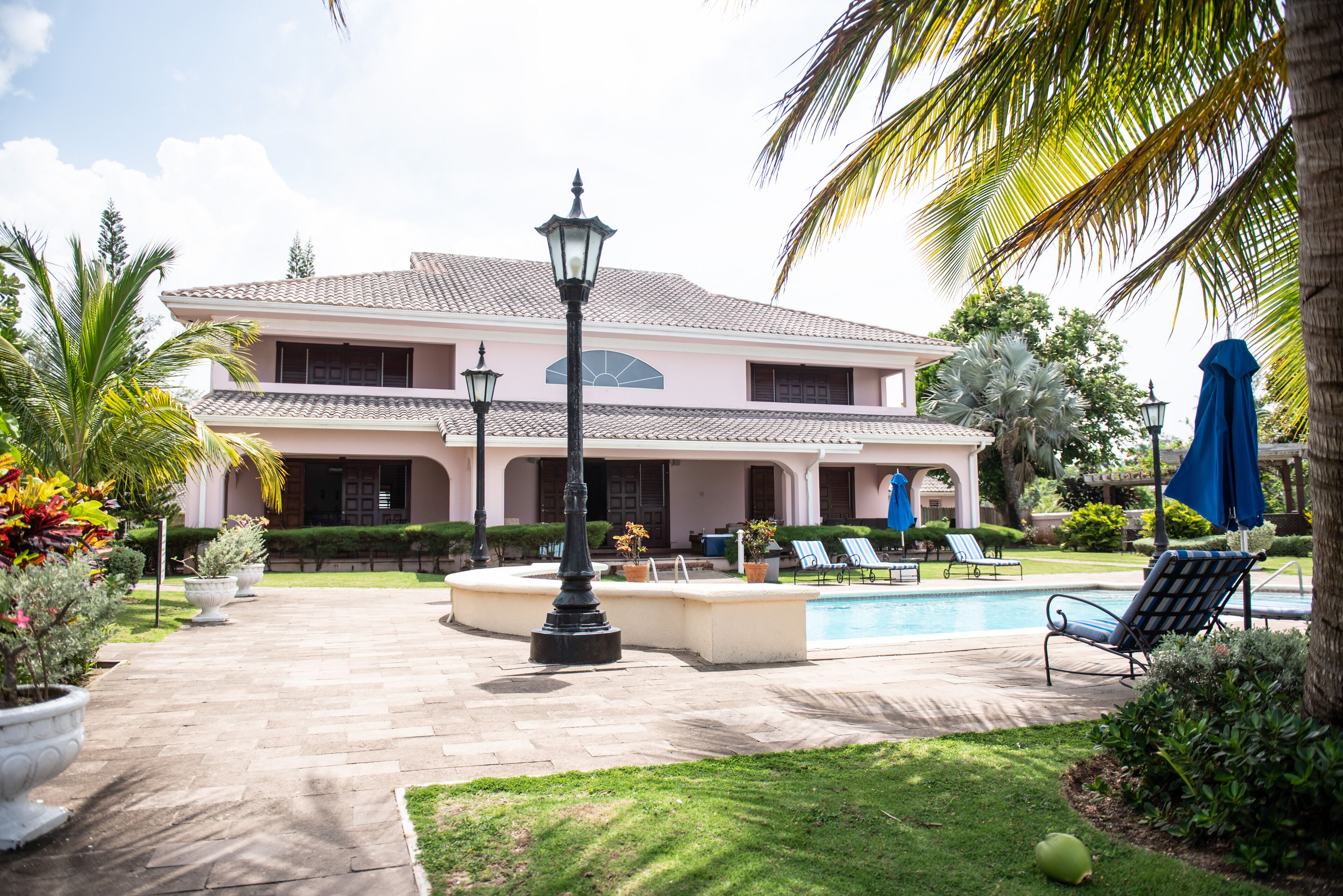 A large house with a swimming pool, outdoor seating, and well-maintained gardens.