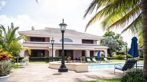 A large house with a swimming pool, outdoor seating, and well-maintained gardens.