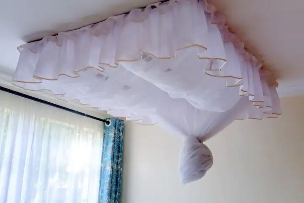 Ein Zimmer mit weißer Decke und einem verzierten, gerafften Vorhang.